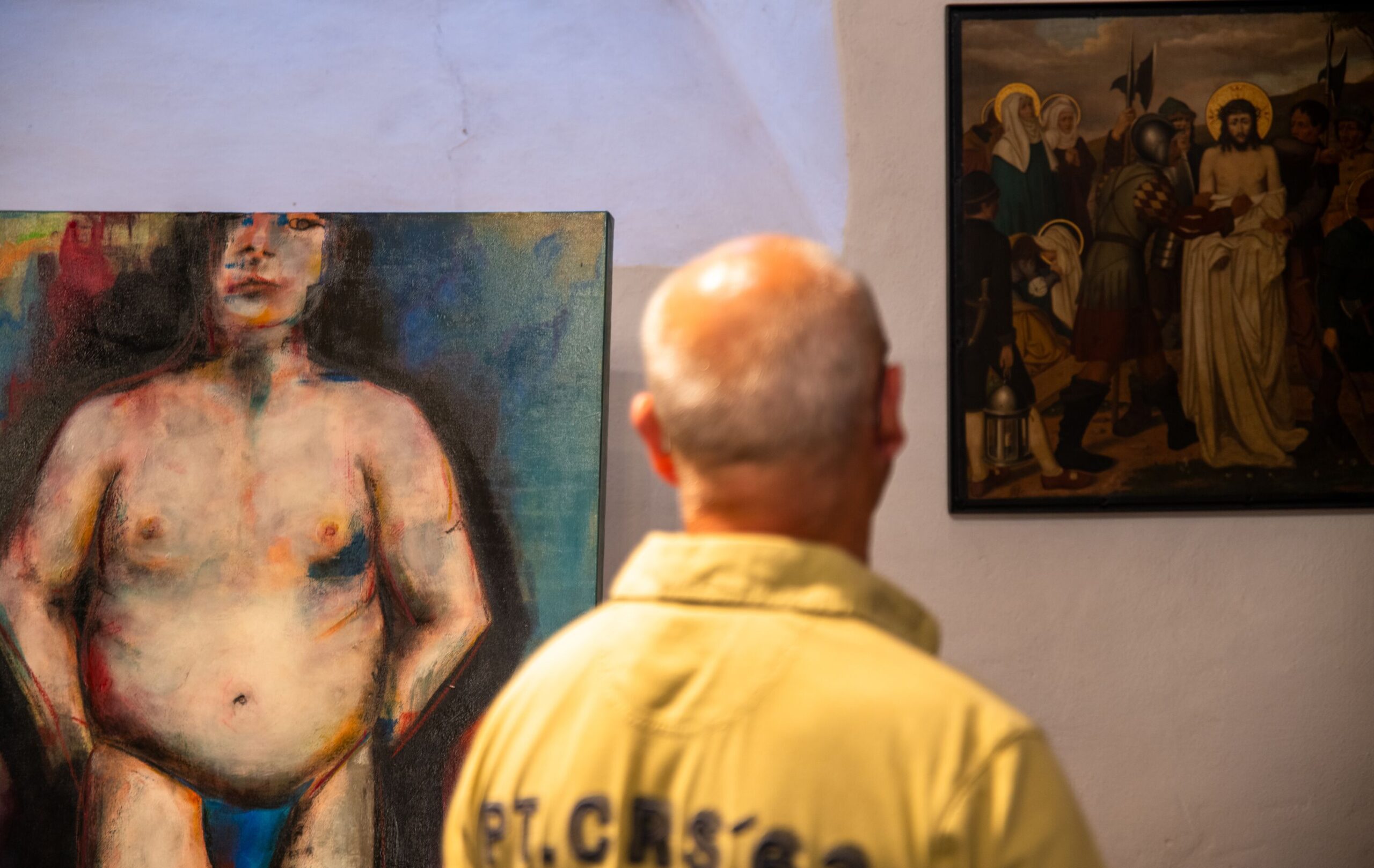 Ein Mann steht vor dem zeitgenössischen Bild "Nackter Mann", das in der Paderborner Gaukirche neben der Kreuzwegstation "Jesus wird seiner Kleider beraubt" hängt.