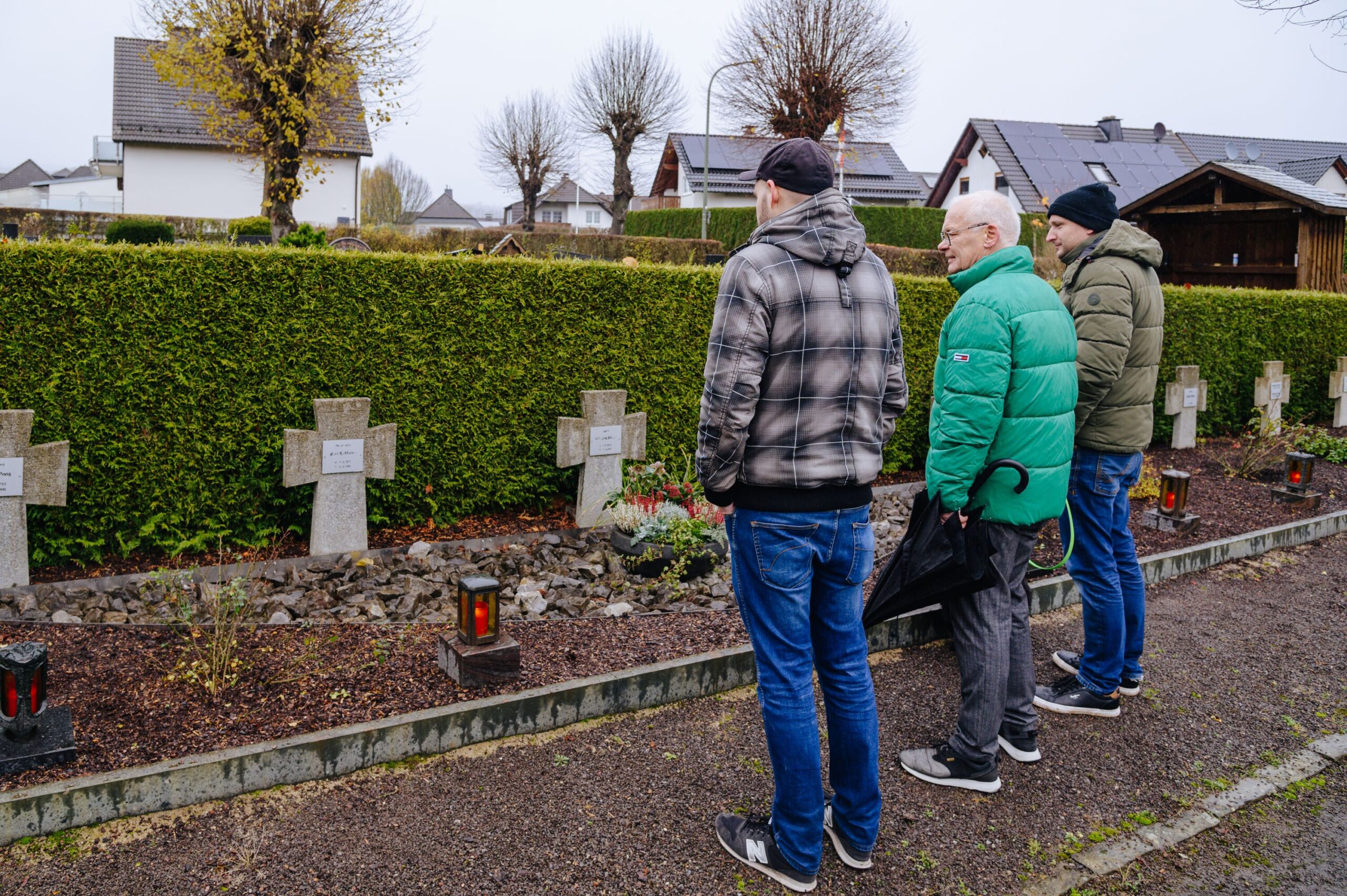 Thomas Pickard, Wolfgang Haase und Nico Mertens stehen vor den von ihrer Gruppe gepflegten Kriegsgräbern.